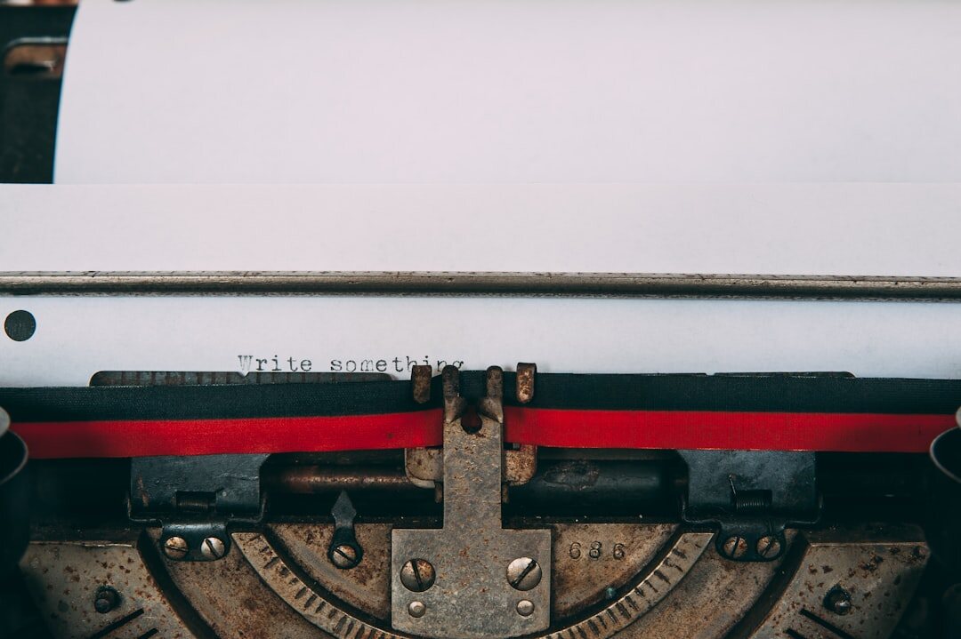 Close-up of a vintage typewriter with paper and a fountain pen on a wooden desk